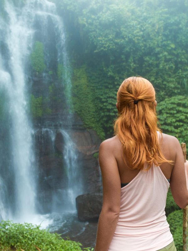 Female adventurer looking at waterfall in Bali jungle